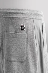 Pantalones cortos de algodón color gris, con cintura elástica ajustable con cordón y parche con logo. Incluye bolsillos laterales y un bolsillo trasero. Presenta bandas laterales a tono, bordado y estampado combinado a contraste en el delantero y la espalda, y aberturas laterales en el bajo.