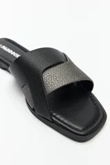 Sandalias bajas plateadas con tiras anchas cruzadas en el empeine y suela plana color marrón.