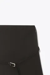 Falda pantalón de tiro medio en color negro, con diseño minimalista y detalle de cinturón fino integrado con hebilla metálica. Cuenta con cierre lateral mediante cremallera oculta.