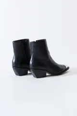 Bota estilo texana de cuero negro con puntera metálica plateada, taco cuadrado y cierre lateral interno.