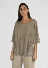 Remera color amarillo con cuello redondo y mangas cortas anchas con detalle de botones en los laterales. Diseño holgado con efecto gastado.