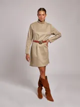 Vestido corto de jersey en color beige, con cuello subido y manga larga. Presenta un corte recto y minimalista.