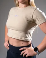 Remera corta color beige con logo estampado en el frente, de algodón elastizado y corte ajustado.