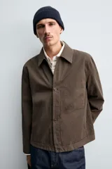 Sobrecamisa de corte regular fit confeccionada en tejido de algodón con acabado lavado. Presenta cuello solapa, cierre frontal de botones, mangas largas con puños abotonados y un bolsillo plastrón en el pecho.