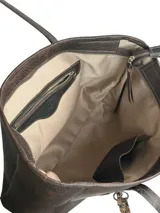 Bolso tipo shopper de cuero marrón chocolate, con doble asa de hombro, cierre superior y bolsillo frontal con cierre y tirador decorativo de cuero con estampa animal print.