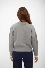 Suéter de tejido de punto color gris, con cuello polo y escote en V ribeteado en color beige. Mangas largas con trenzas en relieve y puños ribeteados en color beige.