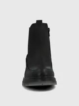 Bota corta tipo Chelsea de cuero negro, con elásticos laterales y suela track gruesa de goma translúcida gris.