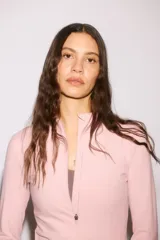 Campera deportiva rosa de corte ajustado, con cuello elevado, cierre frontal completo y mangas largas con abertura para el pulgar.