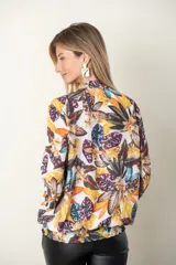 Blusa estampada con hojas en tonos mostaza, verde y blanco. Tiene cuello con lazo, manga tres cuartos y cintura fruncida.