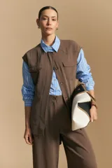 Chaleco de corte sastrero color marrón, con cierre frontal de botones, bolsillos con solapa en el pecho y diseño estructurado.