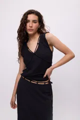 Top sin mangas color blanco, confeccionado en algodón, con escote en V y detalle de tiras cruzadas en el frente.