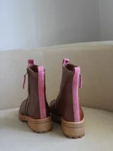 Botas cortas de cuero blanco con suela track marrón y detalles en gamuza beige en la parte frontal y trasera. Cuenta con cierre lateral y tirador de cuero.