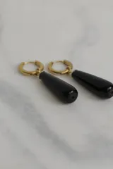 Aros tipo argolla con dije colgante en forma de gota de piedra natural en tonos marrones. Fabricados en acero quirúrgico dorado.