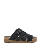 Sandalia tipo slide de color negro con diseño de tiras cruzadas y hebilla metálica ajustable. Presenta una textura grabada tipo reptil en la capellada, plantilla anatómica con borde de corcho y suela de goma plana.