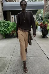 Pantalón de tiro medio con pinzas delanteras, bolsillos laterales y falsos bolsillos de vivo en la parte trasera. Presenta un corte holgado que se estrecha hacia el tobillo, con bajo acabado en pliegues y cierre frontal con cremallera, botón interior y gancho.