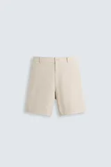 Bermuda color beige confeccionada en tejido de algodón y lino, de corte regular fit. Cuenta con bolsillos frontales y traseros, cierre frontal con cremallera y botón.
