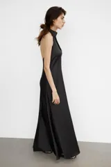 Vestido largo de satén con cuello halter y escote fluido. Presenta un diseño de espalda descubierta con cierre de cremallera oculta y lazada ajustable en el cuello.
