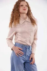 Camisa color beige con cuello clásico, cierre frontal con botones y detalle de flecos metálicos en el cuello.