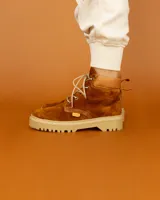 Bota acordonada de cuero color marrón óxido con suela de goma color beige.