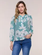 Blusa de gasa texturizada color verde con estampado floral blanco, cuello mao con escote en V y botones frontales. Cuenta con mangas 3/4 abullonadas y detalles de puntilla calada en el pecho.