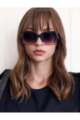 Lentes de sol Tiwi Mali con montura cuadrada de acetato negro y rosa, y lentes degradadas en color gris oscuro.