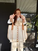 Bolso tipo tote de cuero color crudo con costuras decorativas en hilo color cuero. Tiene doble asa de cuero color cuero y forro interior de tela.