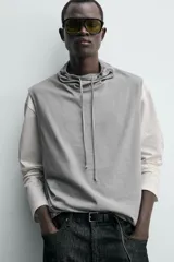 Camiseta sin mangas de corte relajado, confeccionada en algodón ligero, con cuello subido ajustable mediante cordones.