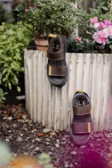 Sandalias marrones con tiras de cuero con ajuste de velcro y detalles en amarillo.