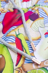 Short de baño con estampado de aguacates, tomates, limones, botellas de salsa picante y tragos de tequila sobre un fondo de rayas horizontales azules y blancas.