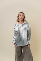 Remera de manga larga con diseño de rayas horizontales verdes sobre fondo crudo, cuello redondo con detalle de volado y cartera frontal con botones.