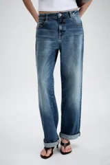 Jeans de tiro medio con diseño de cinco bolsillos, pernera holgada y bajo con vuelta. Cierre frontal con cremallera y botón.