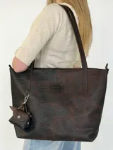 Cartera tote Chabas modelo Molly, confeccionada en cuero genuino color marrón chocolate. Presenta diseño amplio con asas largas de hombro, costuras visibles, parche frontal con logo grabado y un pequeño monedero colgante removible con broche a presión.
