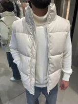 Chaleco puffer de cuerina color beige, con diseño acolchado, cuello alto y cierre frontal completo.