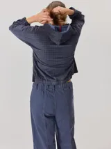 Pantalón de corte relajado color marrón oscuro, con costuras en hilo rojo a contraste y bordado decorativo en el bolsillo delantero.