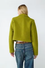 Campera corta de tejido piqué con textura marcada, cuello camisero y cierre frontal de botones. Presenta un calce estructurado y diseño moderno.
