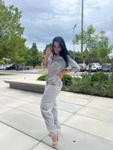 Mono largo gris con textura arrugada, cuello camisero, cierre frontal, bolsillos con solapa en el pecho y bolsillos cargo en las piernas. Incluye cordón ajustable en la cintura y mangas 3/4 con botón.