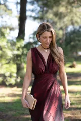 Vestido largo de tafeta color bordó, de corte estilo reloj de arena, sin mangas y con escote en V pronunciado.