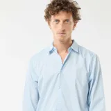 Camisa de manga larga celeste con estampado de pequeños lunares oscuros, corte regular, cuello camisero clásico y cierre frontal de botones.