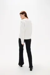 Sweater de punto color blanco, con cuello en V, manga larga y diseño holgado.