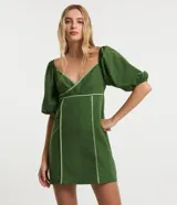 Vestido corto de tricolina color verde oscuro con detalles de bies en tono verde claro contrastante, escote cruzado en V, mangas cortas abullonadas y cierre en la espalda.