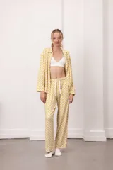 Conjunto de dos piezas compuesto por una camisa de manga larga con cuello camisero y botones frontales, y un pantalón de corte recto. Ambas prendas presentan un estampado geométrico de círculos bicolores.