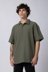 Chomba de manga corta con cuello polo, confeccionada en tejido de punto acanalado de textura pesada. Presenta un calce relajado y cuenta con una pequeña etiqueta distintiva en el ruedo.