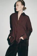 Camisa de corte oversize confeccionada en mezcla de viscosa, con diseño de rayas verticales, cuello solapa, manga larga con puños, bolsillo de plastrón en el pecho y cierre frontal con botones.