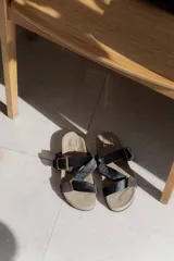 Sandalias de diseño anatómico con tiras cruzadas de pelo sintético negro y detalles en cuero marrón. Cuentan con hebillas metálicas ajustables y plantilla ergonómica.