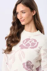 Buzo tejido en jacquard con estampado floral en tonos azul y marrón sobre base color crema. Presenta cuello redondo y puños acanalados.