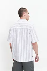 Camisa de manga corta a rayas verticales blancas y grises, con cuello camisero y corte recto. El modelo usa talle M.