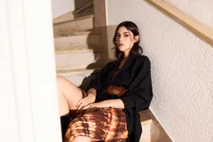 Vestido largo strapless, ajustado al cuerpo, con estampado batik en tonos marrones y naranjas.