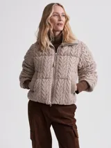 Campera puffer beige con cuello alto acanalado, cierre frontal con cremallera y bolsillos laterales.