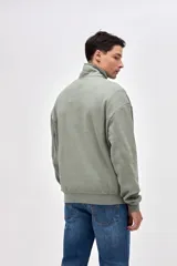 Buzo de felpa con friza, color negro, con cuello alto y cierre frontal parcial. Presenta bordado de la marca en el pecho y un calce relajado.