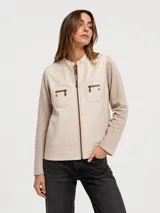 Chaqueta bicolor en tonos beige y tostado, con frente de cuero sintético y mangas y espalda de tejido de punto. Cuenta con cuello mao, cierre frontal y bolsillos frontales con cierre.